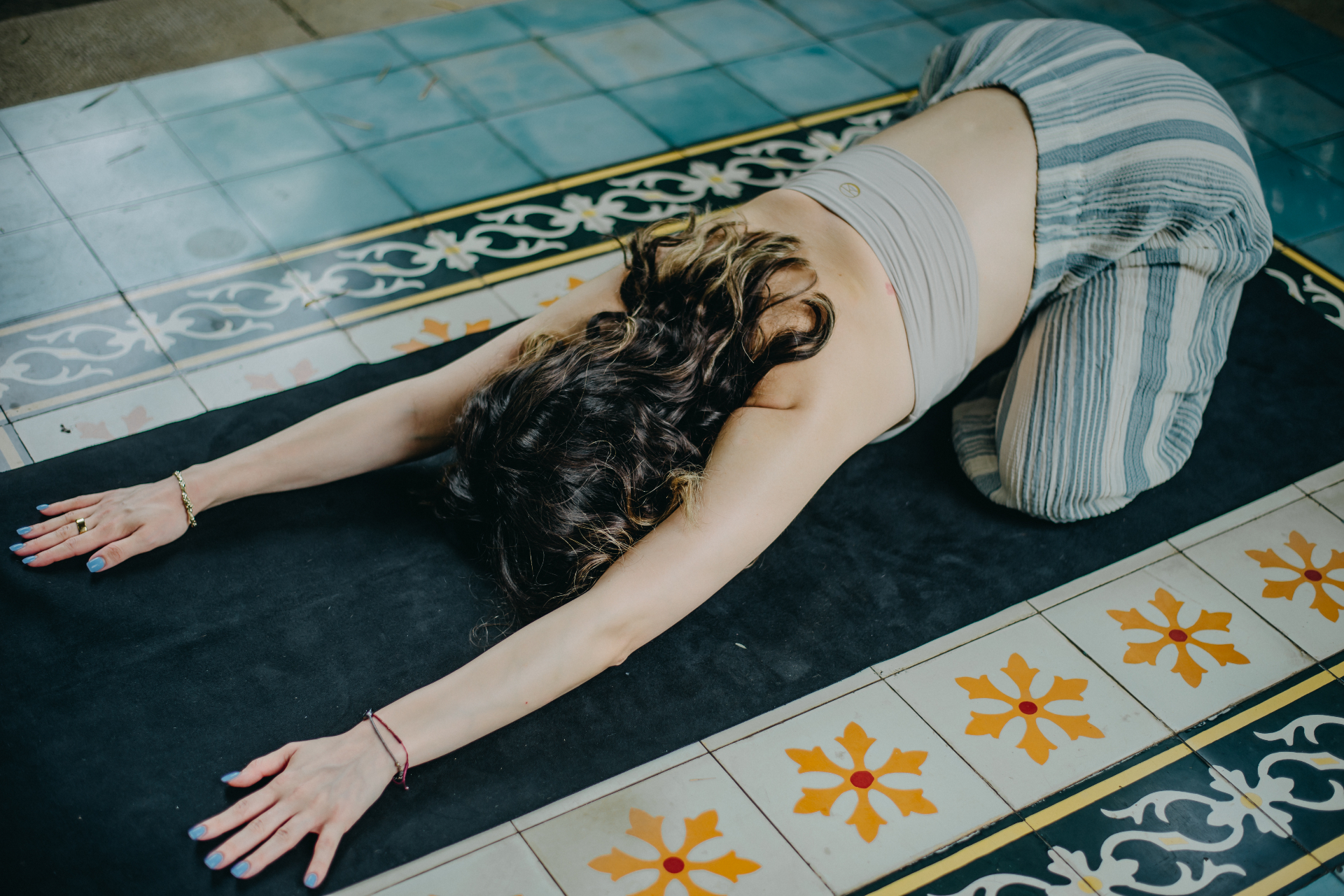 Sena in a pilates child's pose on patterned tiles